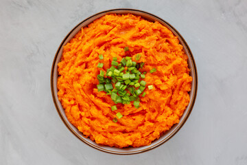 Homemade Creamy Mashed Sweet Potatoes with MIlk and Butter in a Bowl on a gray background, top view. Flat lay, overhead, from above.