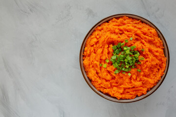 Homemade Creamy Mashed Sweet Potatoes with MIlk and Butter in a Bowl on a gray background, top view. Space for text.
