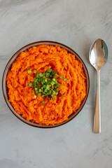 Homemade Creamy Mashed Sweet Potatoes with MIlk and Butter in a Bowl on a gray background, top view.