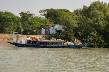 Fototapeta na wymiar 11th February, 2023, Sundarban, West Bengal, India: A ferry boat carrying daily needs items anchored on the jetty of river at Sundarban Tiger reserve, India.