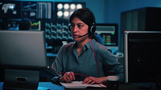 Concentrated customer service woman, looking for solutions on the laptop computer for a client's problems, writing their data in a notepad sitting at desktop. Support service concept. High quality 4k