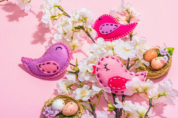 Gentle Easter composition with cherry flowers and handmade felt birds. Decorative eggs and nest