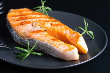 Fried salmon steak on black wooden table