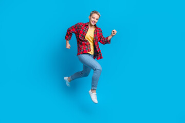 Fototapeta na wymiar Full length photo of active pleasant good mood woman wear checkered shirt jeans running rush on sale isolated on blue color background