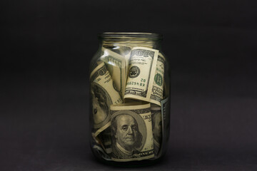 A glass jar full of dollars between one dollar bills. An easy way to save real money © Angelov