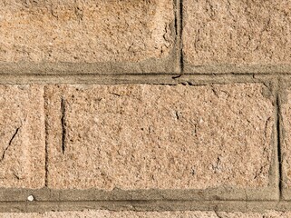 texture of the stone. A yellow stone decorated in the form of a brick in bright sunlight.