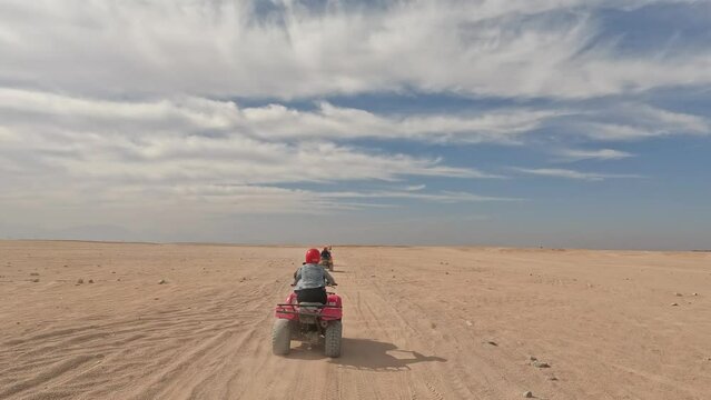 Pov shot of quad bike tour in sandy desert during sunny day in summer