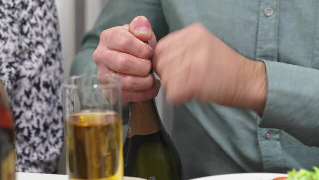 men's hands open a bottle of champagne.
