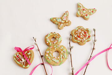  Mental gifts for women's day: gingerbread in the shape of hearts, butterflies, flowers, number 8 with willow branches and bright ribbons on a white background, top view