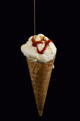 Sorvete de creme com calda escorrendo em fundo preto. 