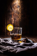 Cognac with lemon. Whiskey with lemon on the table. Incident beam of light on a glass. Glass on the bar.