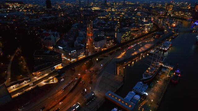 Aerial drone view of Hamburg at evening, Germany. Elbe coastline, moored boats, sea port, classic and modern buildings, roads with cars and nightlights
