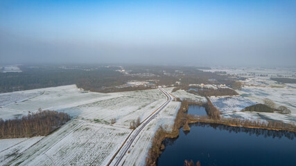 Aerial landscape of the frozen lake and forest in the snow in Belgium at sunset shot by a drone. High quality photo