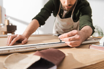 Cropped view of craftsman restoring wooden picture frame in workshop.