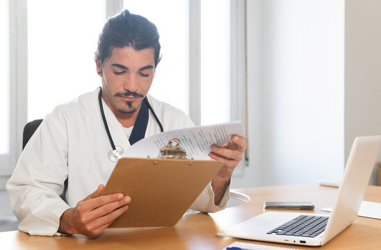 Focused doctor checking information on clipboard