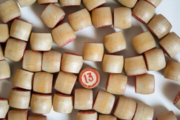 A lot of barrels from the lotto on a white background. Among the wooden barrels stands out with the number 13. Barrels are wooden with red numerals.