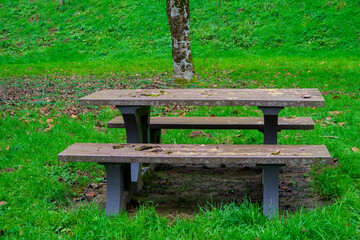 Empty benches with tables for tourists to rest on the green grass near the river. A place of rest for tourists and travelers.