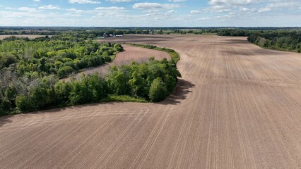 Fototapeta premium Vast farmland with corn fields beside Lake Ontario in up state New York under blue sky and clouds