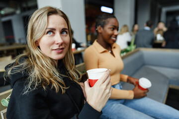 Two young women friends enjoying coffee together in a coffee shop