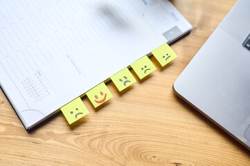 Lachende und traurige Gesichter auf post it Zettel in einem Notizbuch auf einem Schreibtisch aus...