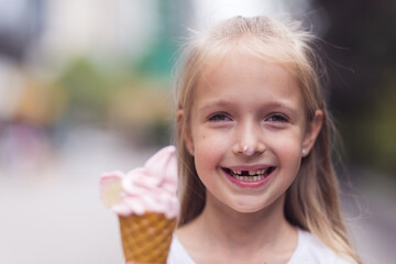 Pretty little caucasian girl with blonde hair eight years old eating licking vanilla ice cream in...