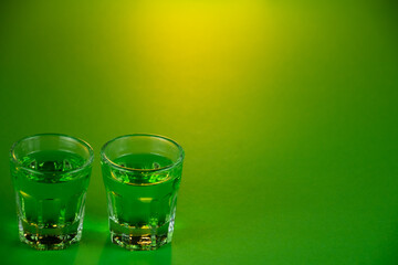 Shot glasses lined up against emerald green theme background waiting to be filled and slammed in...