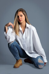 Young woman in the studio, in a white shirt posing on a white background