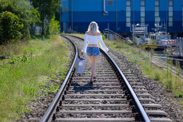 Back view of a blond woman  on train tracks