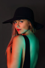 Young woman with hat in studio posing on black background