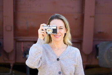 Smiling woman with an old camera taking a picture