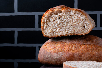 Sourdough rye bread without yeast against black brick wall. Slice of homemade bakery product