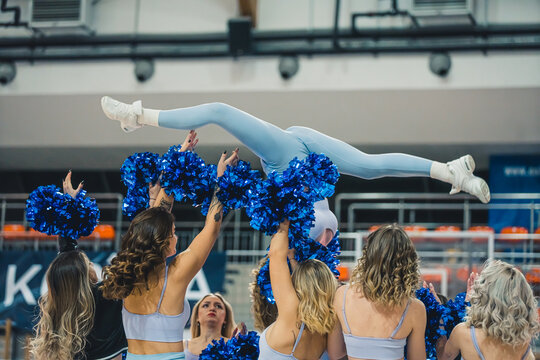 cheerleaders holding a girl up doing a split in the air, indoors. High quality photo