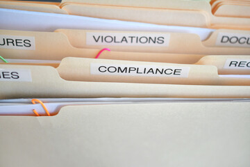 Compliance in the workplace. Folders labeled Compliance, Violations in focus.