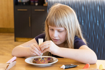Caucasian Child (7-8 years old) decorating edible gingerbread man 