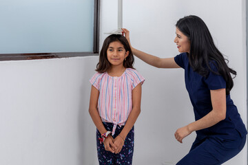 Close-up of a doctor fearing the height of a girl in her medical office.