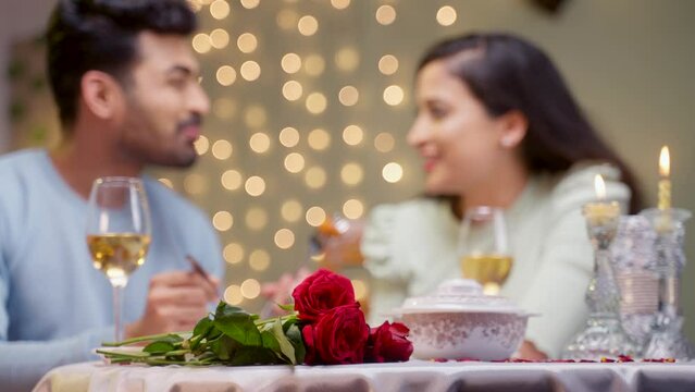 Rack focus shot of happy young couple having candle light dinner during valentines day celebration - concept of dating, enjoying eating food, romantic evening