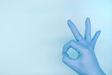 hand in medical glove showing ok sign on blue background