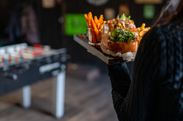 Waiter hold a plate with tasty food in pub