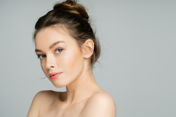 Young woman with natural makeup looking at camera isolated on grey.
