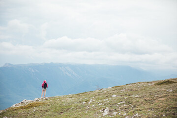a woman on a hike stands on a mountain and looks at the mountains nature hiking journey