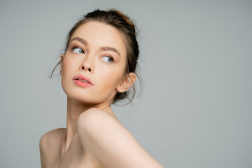 Young woman with naked shoulders looking away isolated on grey.