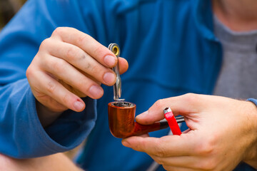 closeup man hands preparing tobacco pipe to smoke