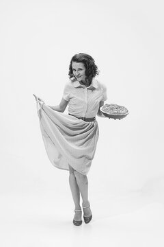 Portrait of beautiful retro woman in vintage fashion style dress holding apple pie. Black and white shot