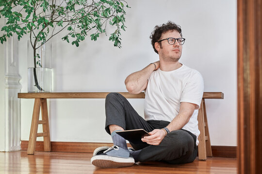 Portrait of a young white man sitting on floor with back ache