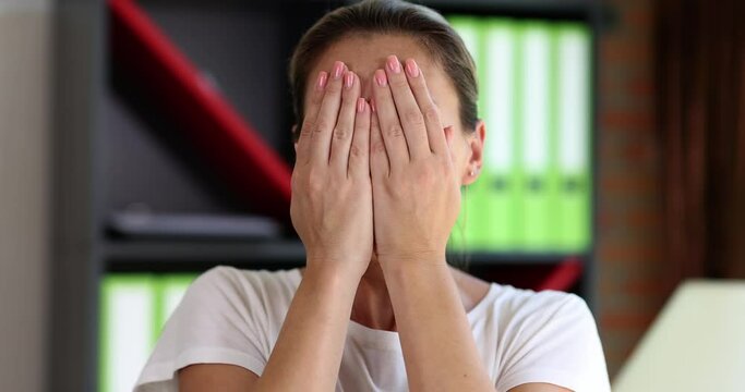 A frightened woman looks through her fingers, a close-up