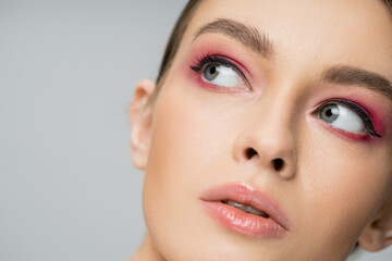 Fototapeta premium close up portrait of pretty woman with perfect skin and makeup looking away isolated on grey.