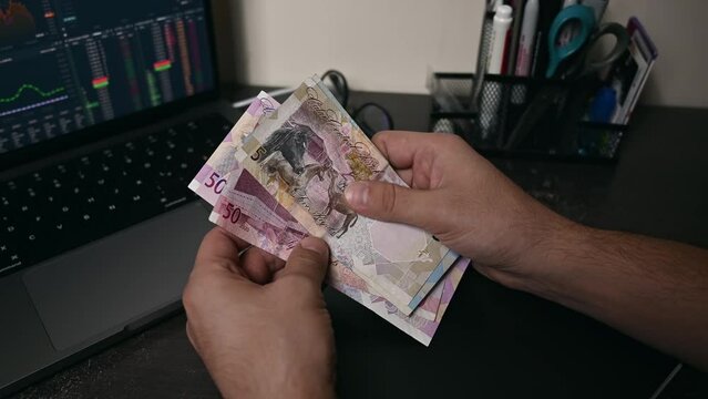 Businessmen counts Qatar money bills on hand, which is called Riyal. Paper banknotes of various denominations