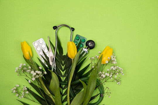Bouquet of flowers and stethoscope on a green background, a place for text, happy doctors day, nurses week and other medical holidays.