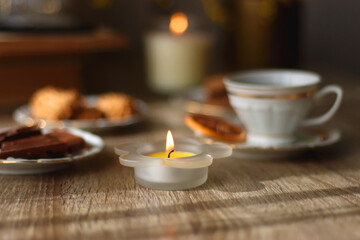 Scented candles, on the table. Selective focus.chocolate, cookies, cup of tea, books, e-reader, glasses and flowers on the table. Hygge at home. Selective focus.