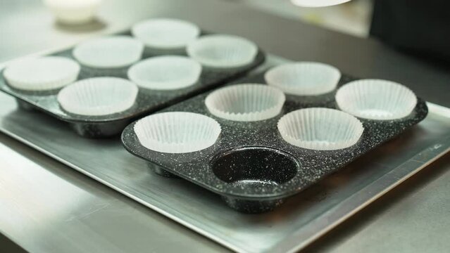 Baker puting paper cupcake liners on grey cupcake pan. Inside. Extrime close up. High quality 4k footage